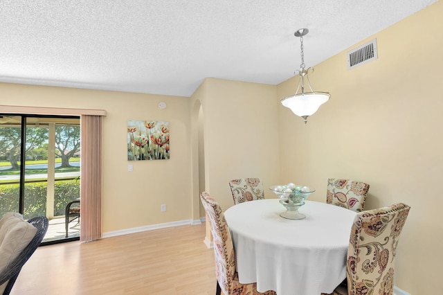 dining space with light hardwood / wood-style flooring and a textured ceiling