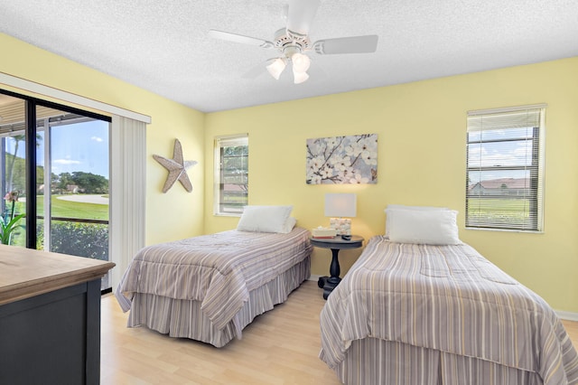 bedroom featuring access to outside, a textured ceiling, ceiling fan, and light wood-type flooring