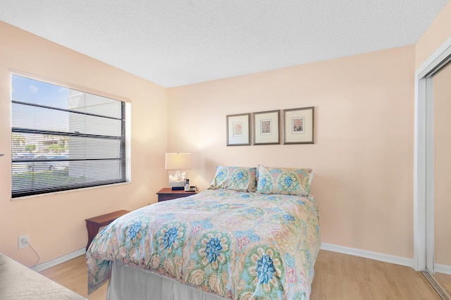 bedroom with a closet, a textured ceiling, and light hardwood / wood-style flooring