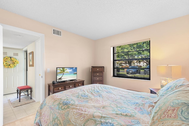 bedroom featuring light tile floors and a textured ceiling