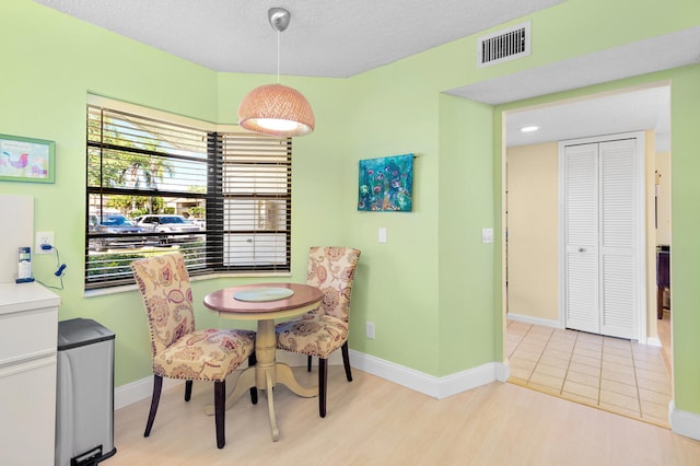 dining area featuring a textured ceiling and light hardwood / wood-style floors