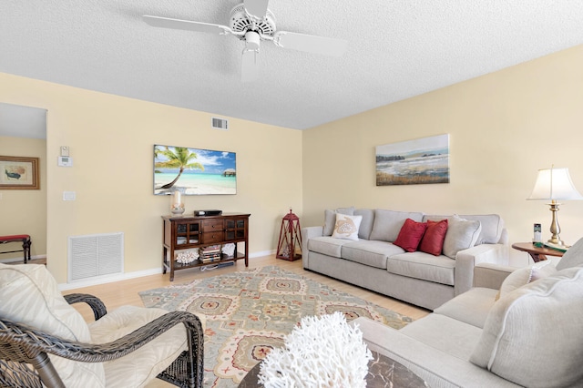 living room featuring light hardwood / wood-style flooring, ceiling fan, and a textured ceiling