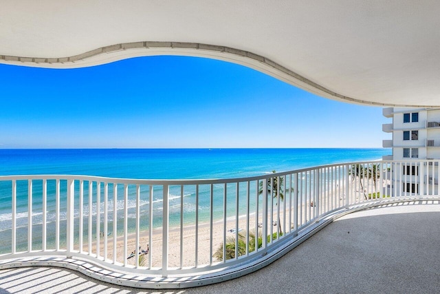 balcony with a water view and a view of the beach