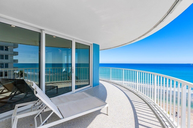 balcony featuring a water view and a beach view