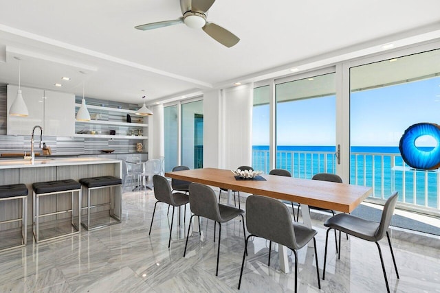 dining room with a water view, sink, ceiling fan, a wealth of natural light, and a wall of windows