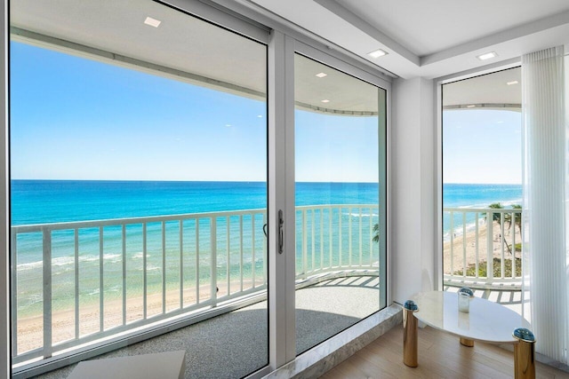 interior space with plenty of natural light, a water view, and a beach view