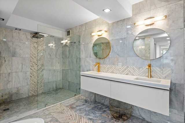 bathroom with vanity, a tile shower, and tile walls