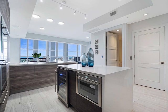 kitchen featuring beverage cooler, plenty of natural light, stainless steel oven, and a center island