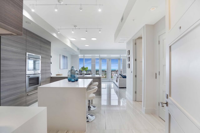 kitchen with double oven, white cabinets, a kitchen bar, and a kitchen island