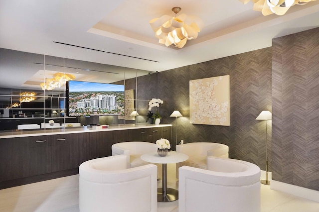 interior space featuring dark brown cabinets, a tray ceiling, pendant lighting, and an inviting chandelier