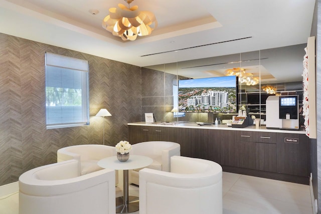 interior space with dark brown cabinetry, a raised ceiling, tile walls, pendant lighting, and light tile patterned floors