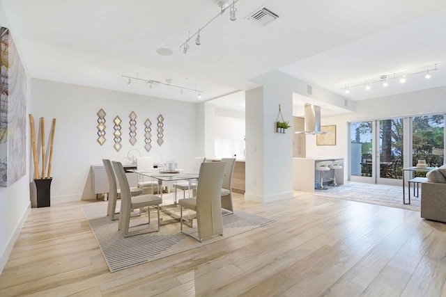 dining area featuring rail lighting and light hardwood / wood-style floors