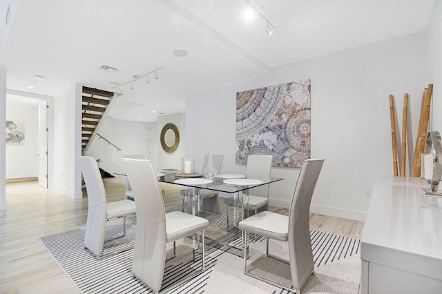 dining area with light hardwood / wood-style floors and rail lighting