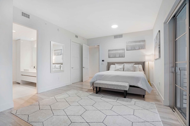 bedroom with ensuite bathroom and light hardwood / wood-style flooring