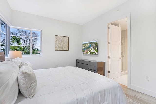 bedroom with ensuite bath and light hardwood / wood-style floors