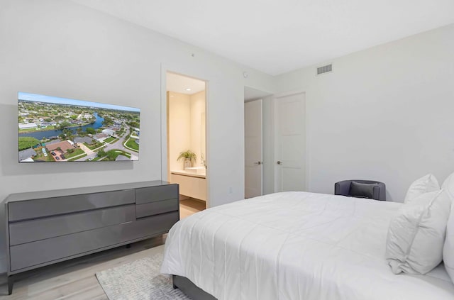 bedroom featuring ensuite bathroom and light wood-type flooring