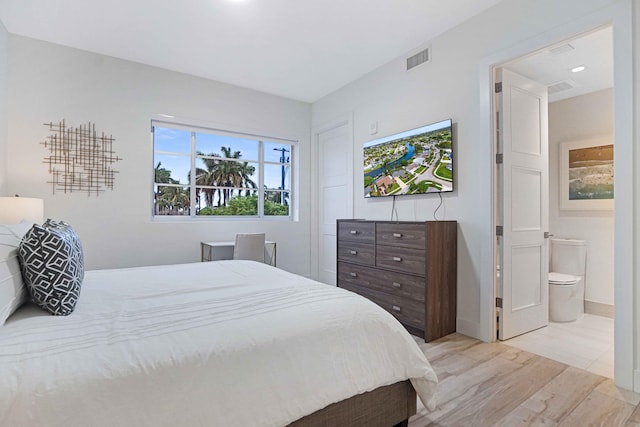 bedroom with ensuite bathroom and light hardwood / wood-style flooring