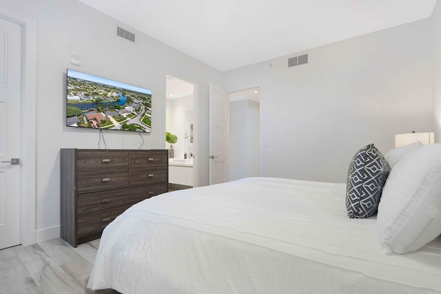 bedroom with ensuite bathroom and light hardwood / wood-style floors