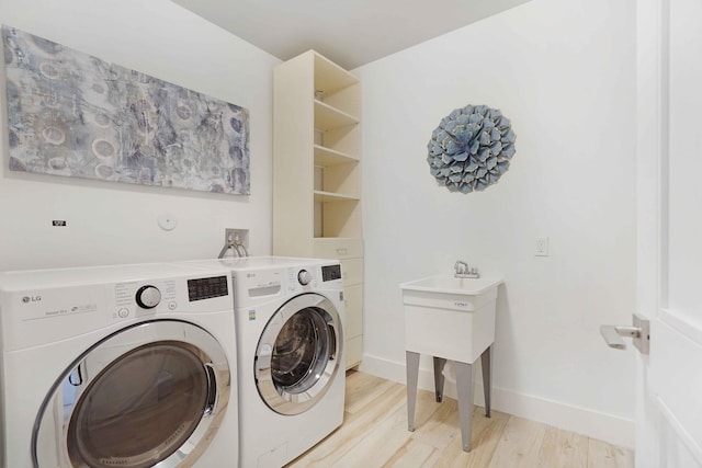 laundry area with washer and clothes dryer and light wood-type flooring