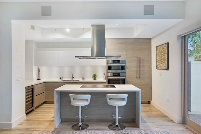 kitchen with black electric cooktop, beverage cooler, light hardwood / wood-style flooring, and island range hood