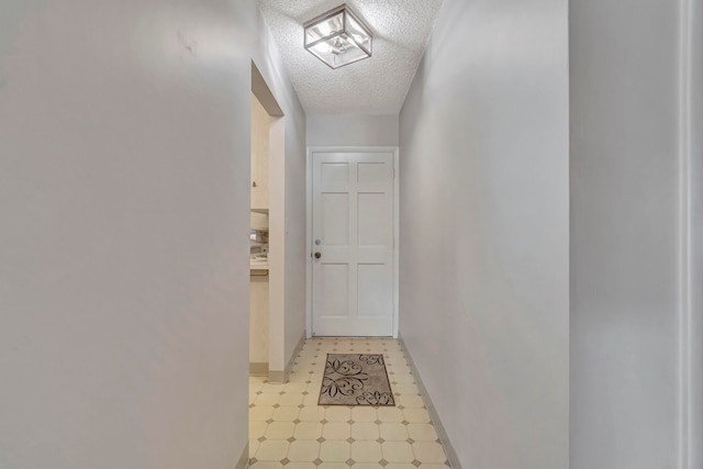 corridor featuring a textured ceiling and light tile floors