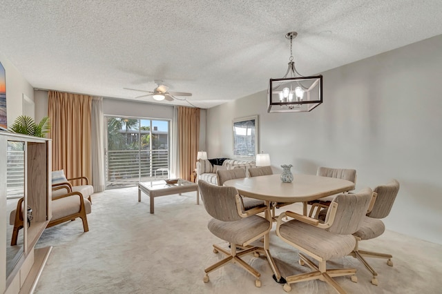 carpeted dining room featuring a textured ceiling and ceiling fan with notable chandelier