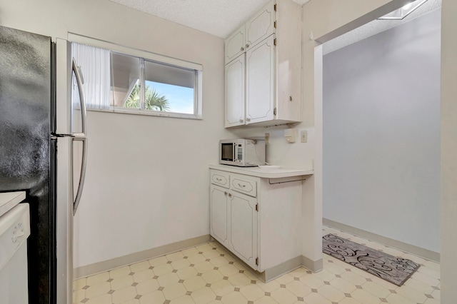 kitchen with light tile floors, white cabinetry, white dishwasher, and stainless steel refrigerator