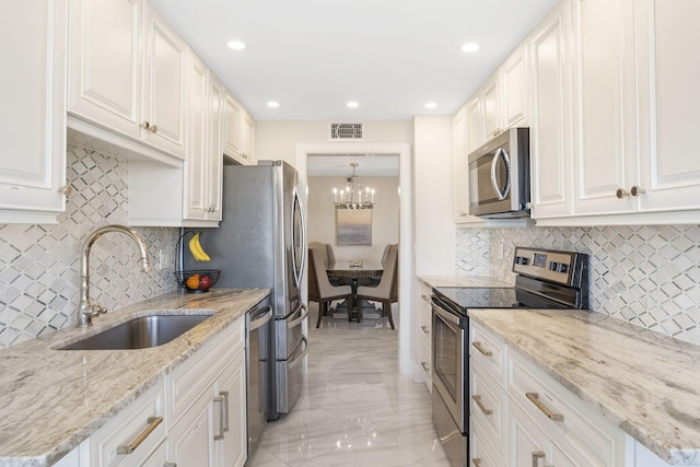 kitchen with tasteful backsplash, an inviting chandelier, appliances with stainless steel finishes, and sink