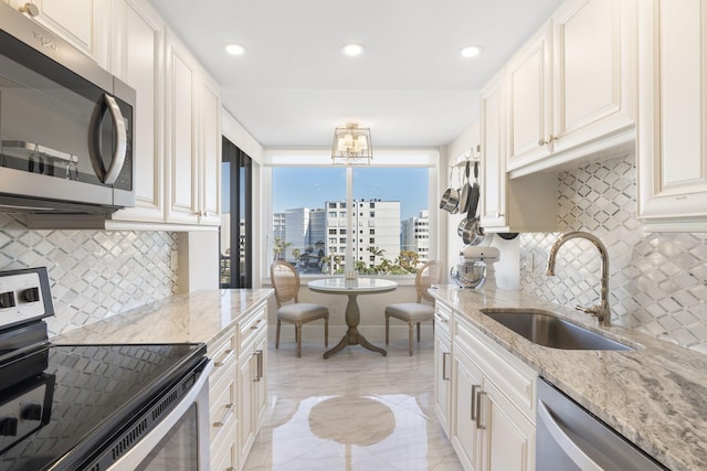 kitchen featuring backsplash, appliances with stainless steel finishes, light stone countertops, and sink