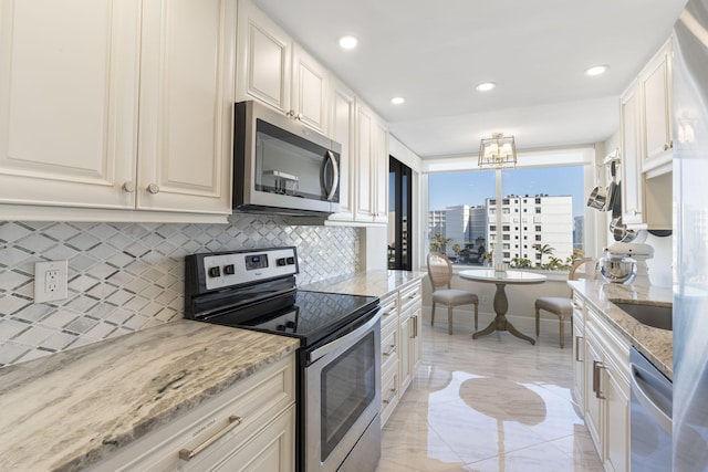 kitchen with appliances with stainless steel finishes, white cabinetry, backsplash, and light stone countertops