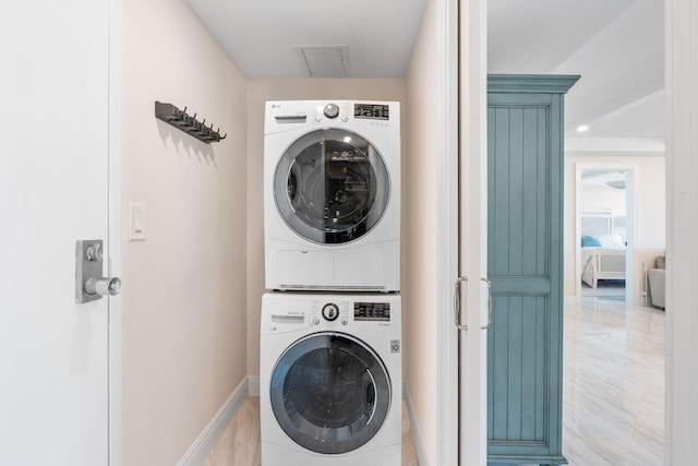 clothes washing area with light tile flooring and stacked washer and dryer