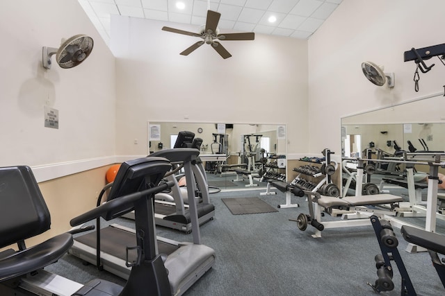 exercise room with high vaulted ceiling, ceiling fan, and a drop ceiling