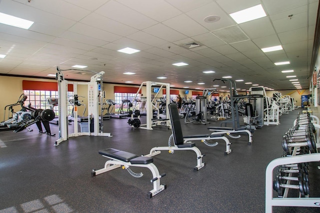 exercise room with a paneled ceiling and a healthy amount of sunlight