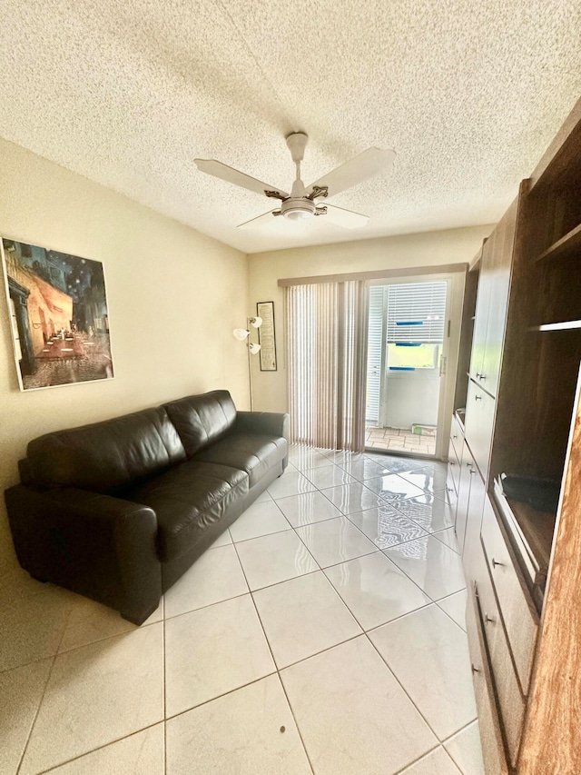 living room with light tile floors, ceiling fan, and a textured ceiling