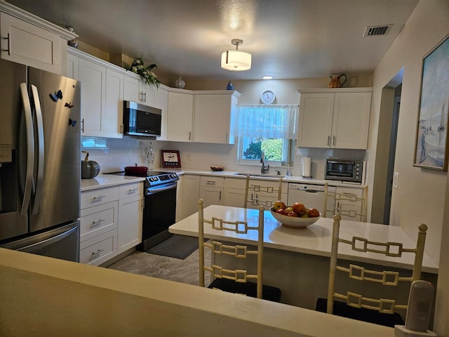 kitchen with appliances with stainless steel finishes, sink, light wood-type flooring, white cabinets, and tasteful backsplash