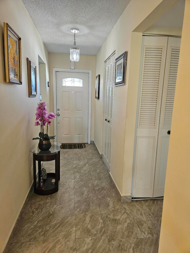 doorway to outside with dark tile floors and a textured ceiling