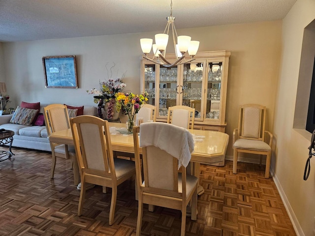 dining space with a notable chandelier, a textured ceiling, and dark parquet flooring