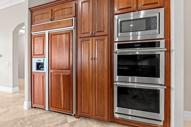 kitchen with built in appliances, ornamental molding, and light tile floors