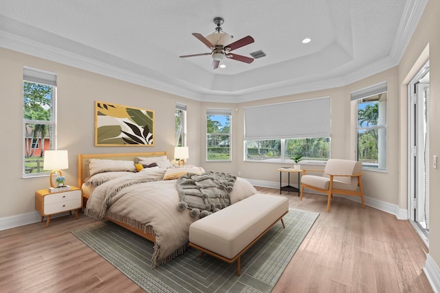 bedroom with hardwood / wood-style floors, multiple windows, ceiling fan, and a raised ceiling