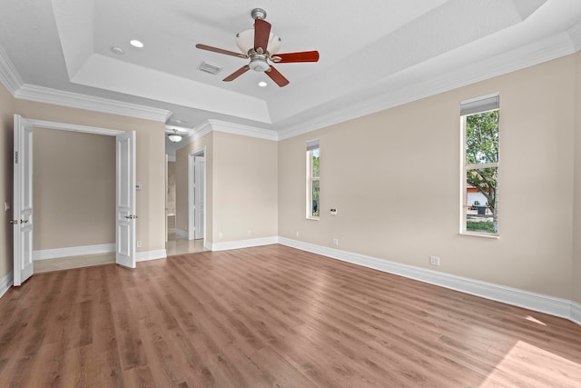 spare room with ornamental molding, a raised ceiling, light hardwood / wood-style floors, and ceiling fan