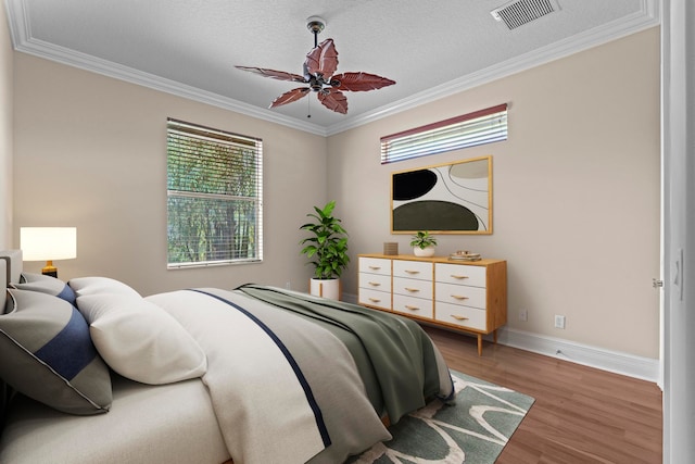 bedroom with a textured ceiling, crown molding, ceiling fan, and hardwood / wood-style flooring