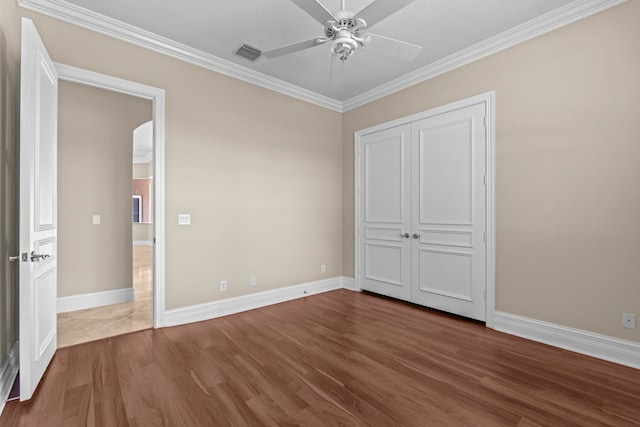 unfurnished bedroom featuring crown molding, a closet, ceiling fan, and dark hardwood / wood-style flooring