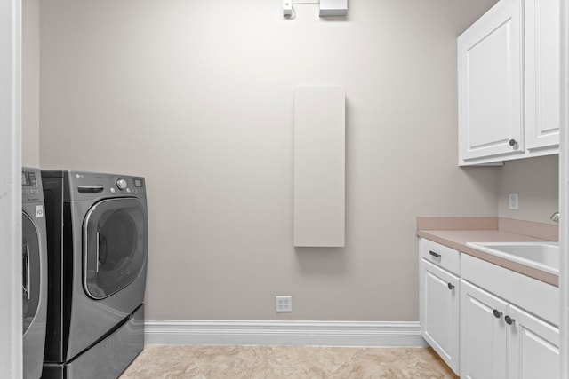 laundry room with washing machine and dryer, light tile floors, cabinets, and sink