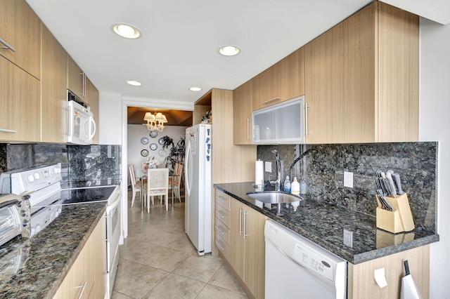 kitchen featuring sink, tasteful backsplash, light tile patterned floors, dark stone countertops, and white appliances