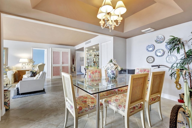 dining area featuring a raised ceiling, tile patterned floors, and an inviting chandelier