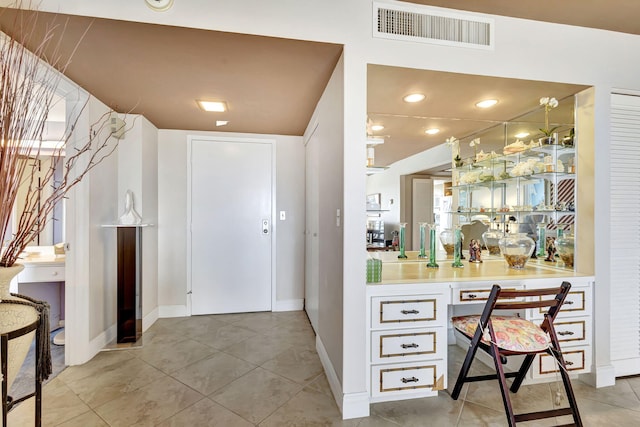 bar with built in desk and light tile patterned floors