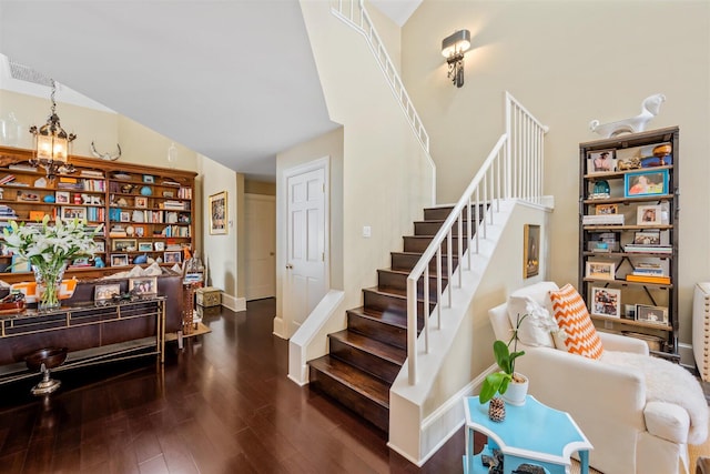 staircase featuring high vaulted ceiling, dark hardwood / wood-style floors, and an inviting chandelier