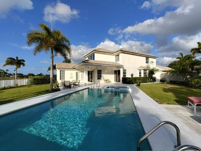 rear view of house with a fenced in pool, a patio area, and a yard