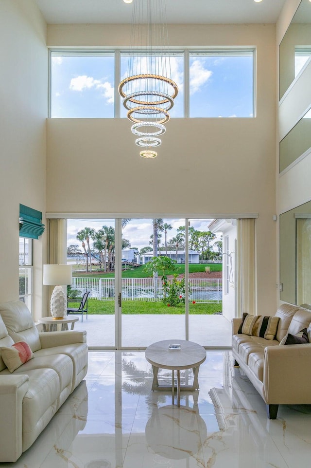 living room featuring a healthy amount of sunlight, a high ceiling, and an inviting chandelier