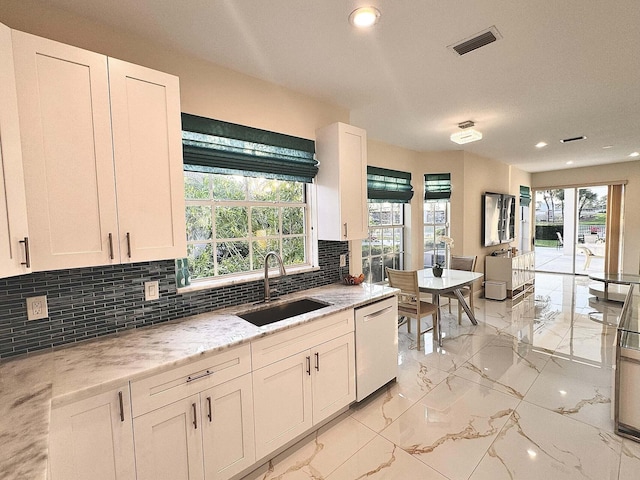 kitchen featuring decorative backsplash, stainless steel dishwasher, sink, and white cabinets